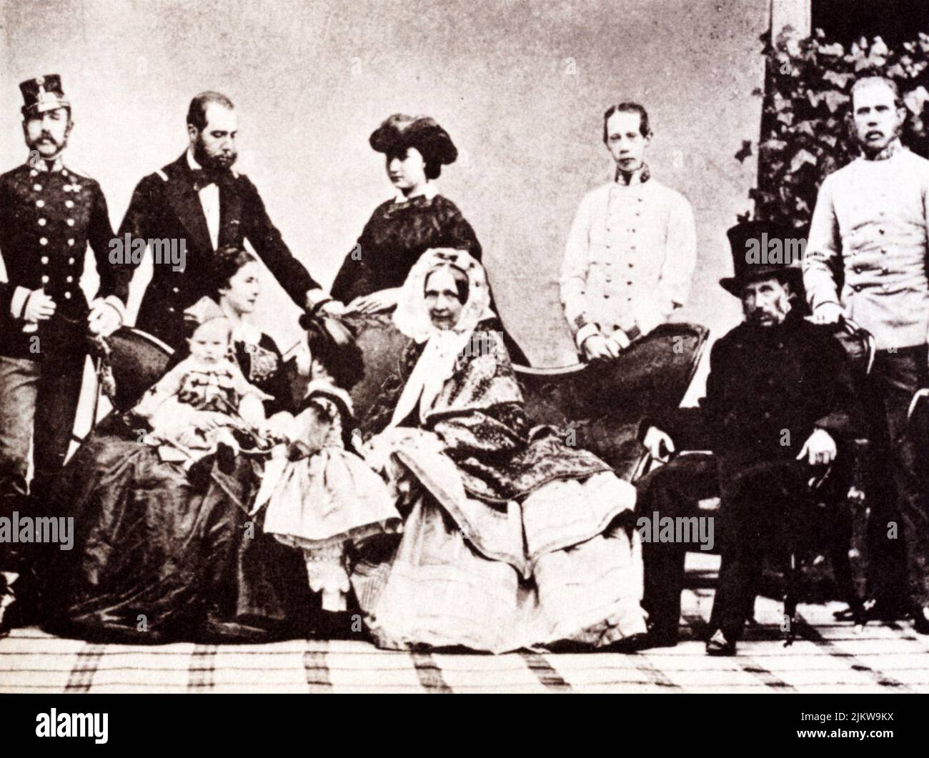 1859 , Wien , Austria   : The celebrated austrian  Empress Elisabeth of HABSBURG   ( SISSI von Wittelsbach  , 1837 - 1898 ) , daughter of Maximillian von Bayern, wife of  Kaiser Franz Josef ( 1830 - 1916 ) , Emperor of Austria , King of Hungary and Bohemia .Seated on couch with little  son RUDOLF ( 1858 - 1889 )  and  daughter  GISELA ( 1856 - 1932 ). Near her the Mother-in-law and aunt Archduchess SOPHIE of Bavaria ( 1805 - 1872 ) with husband FRANZ KARL ( 1802 - 1878 ) of Habsburg . Standing (from left ) the 3 brothers : The Kaiser FRANZ JOSEF , Ferdinand MAXIMILIAN (future 1864  Emperor of Stock Photo