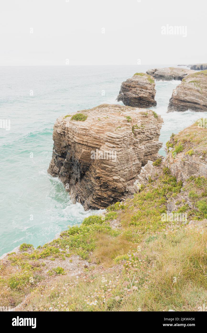 Cliffs next to the Cantabrian Sea, located in Asturias, with its characteristic green vegetation in the surroundings. Vertical shot, concepts. Stock Photo