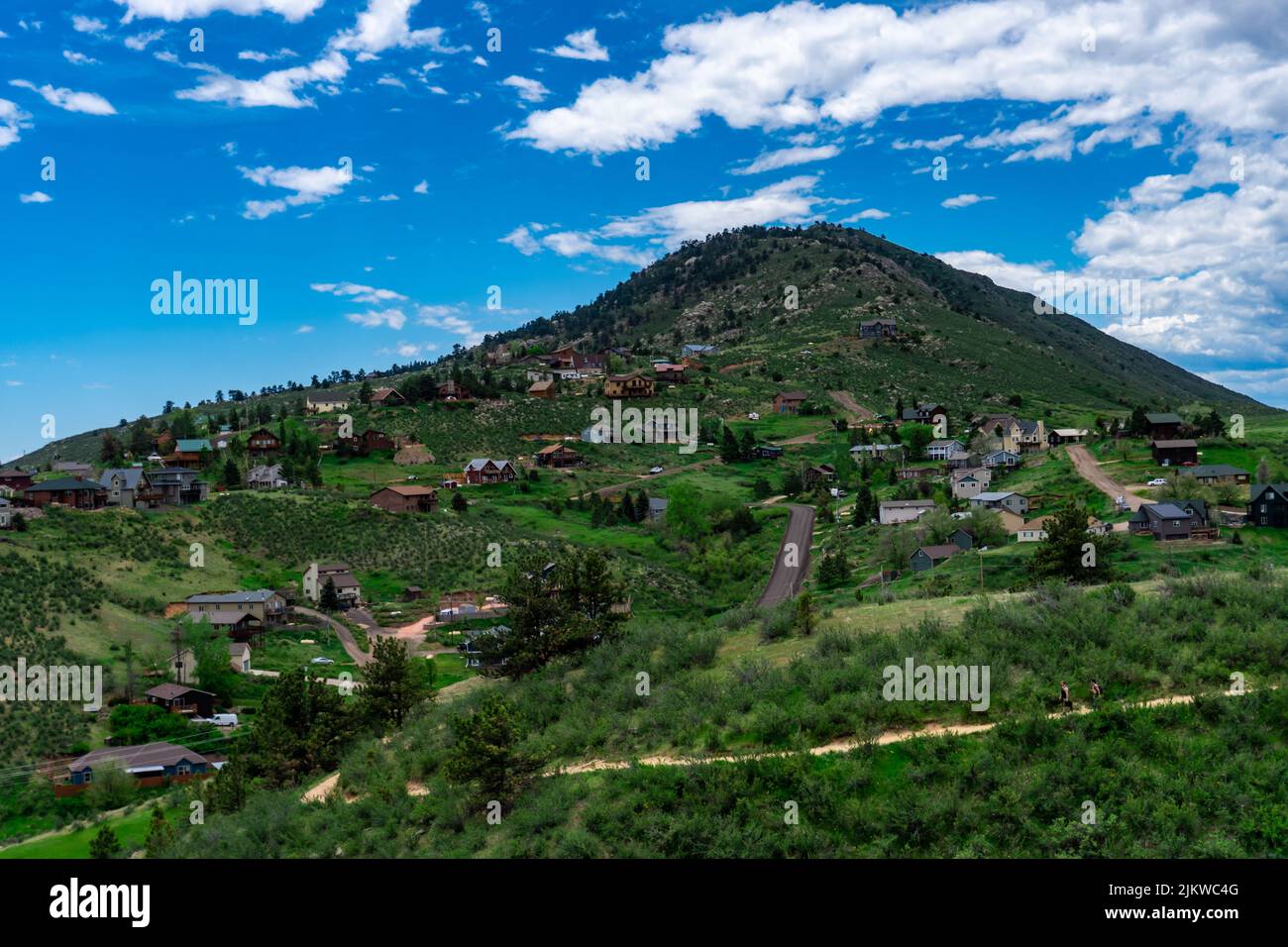 A beautiful shot of houses over green landscape with mountain covered with green under cloudy sky Stock Photo