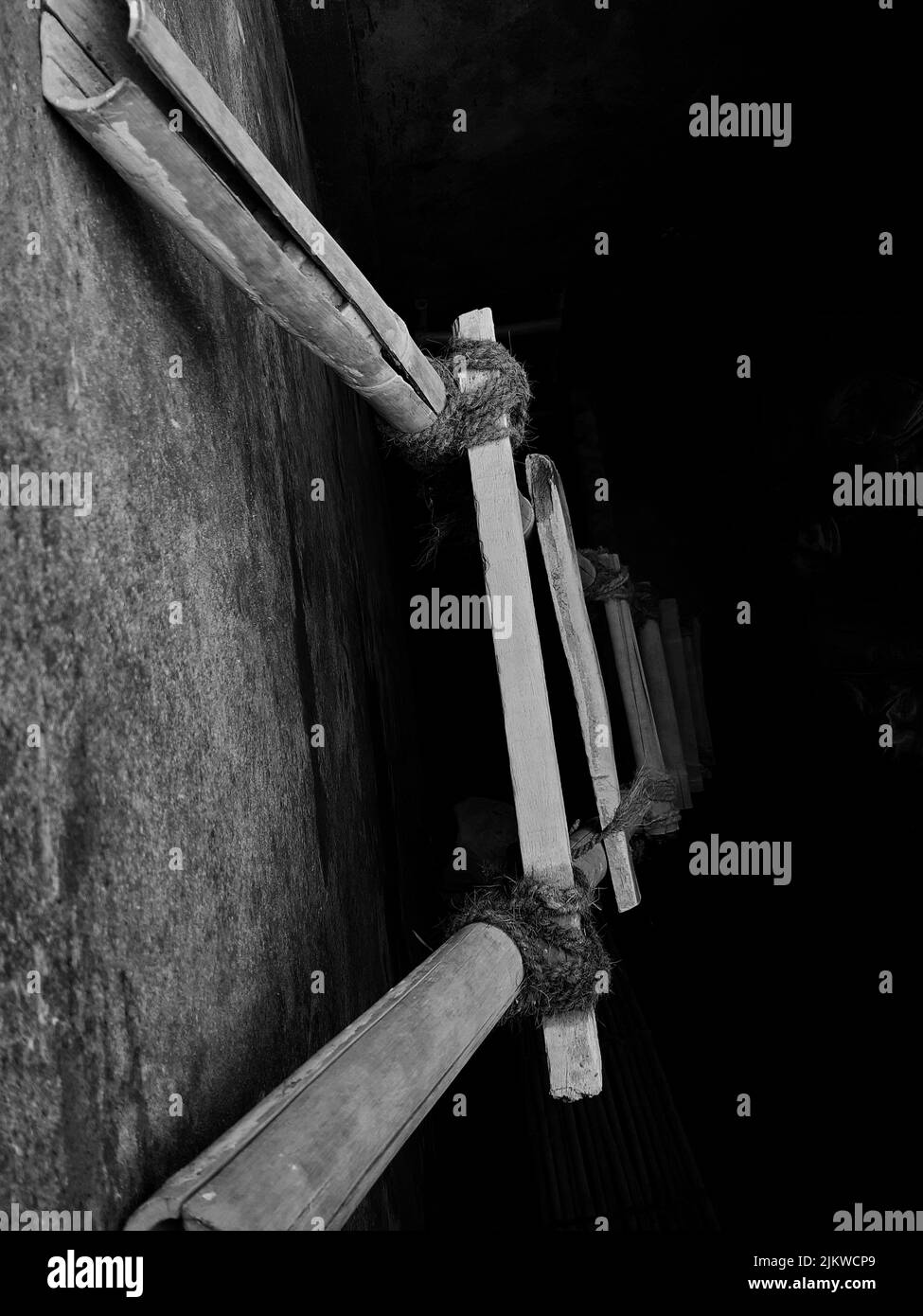 A grayscale top view of a ladder made of wood and ropes hanging on a ...