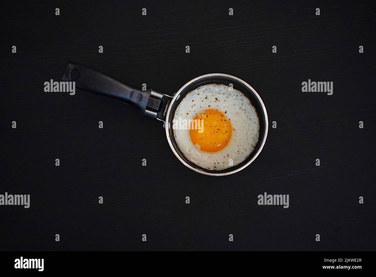 Fried eggs in a pan and a black background Stock Photo