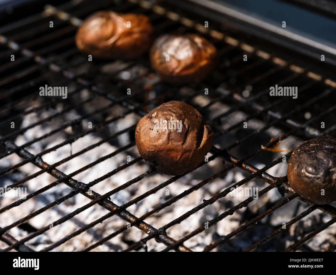 Potatoes baked on a grill grid. Close-up Stock Photo
