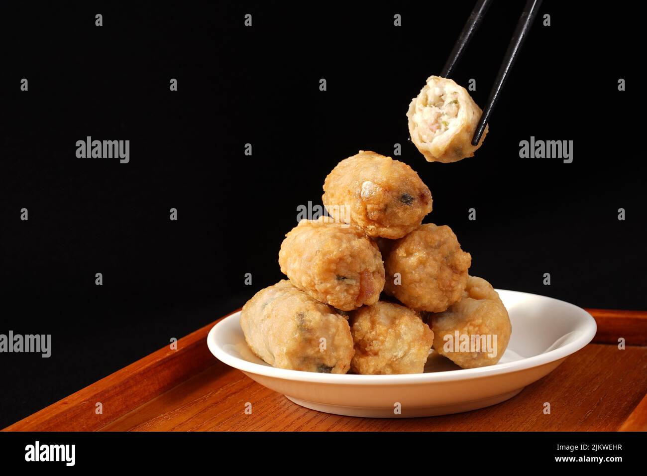 A closeup of chicken meatballs one over another with chopsticks on the white plate Stock Photo