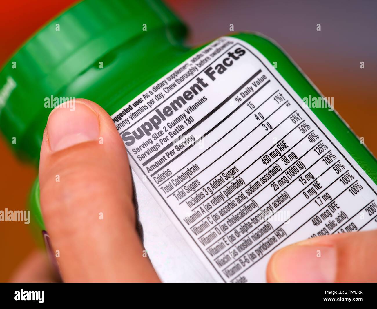 A woman holding a vitamin supplement jar with a supplement facts label at the back. Stock Photo