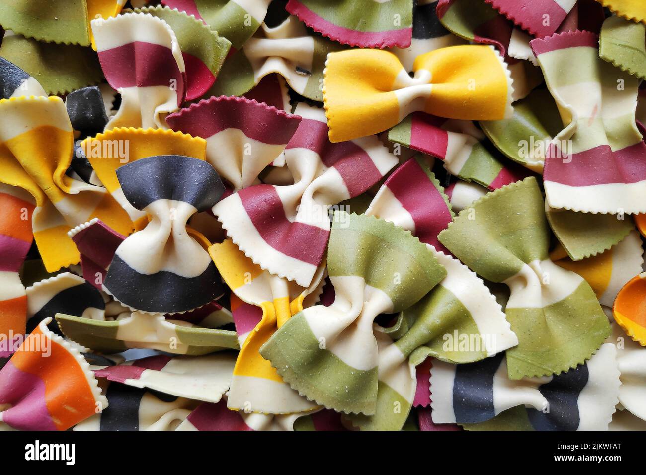 Close-up on a stack of uncooked multi colorful striped farfalles from Italy. Stock Photo