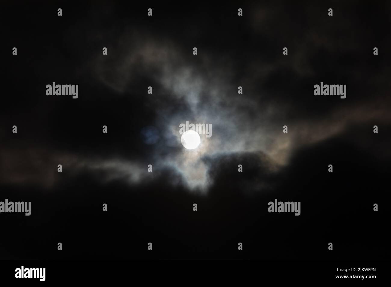 The Moon in a cloudy night sky Stock Photo