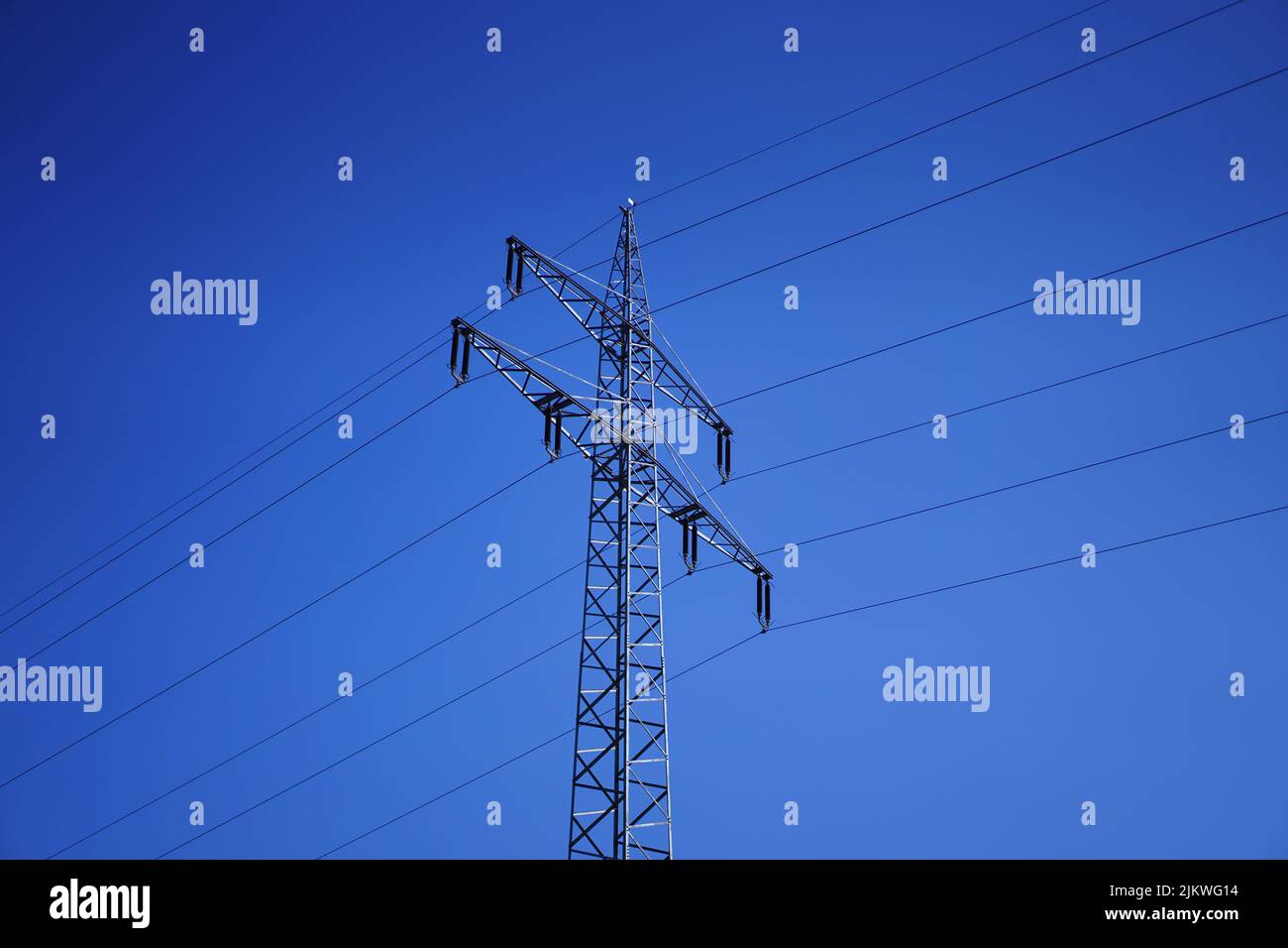 A low angle shot of a high voltage transmission tower against blue sky background Stock Photo