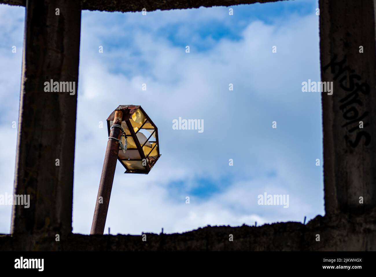 A closeup of an old broken street light viewed from a window frame