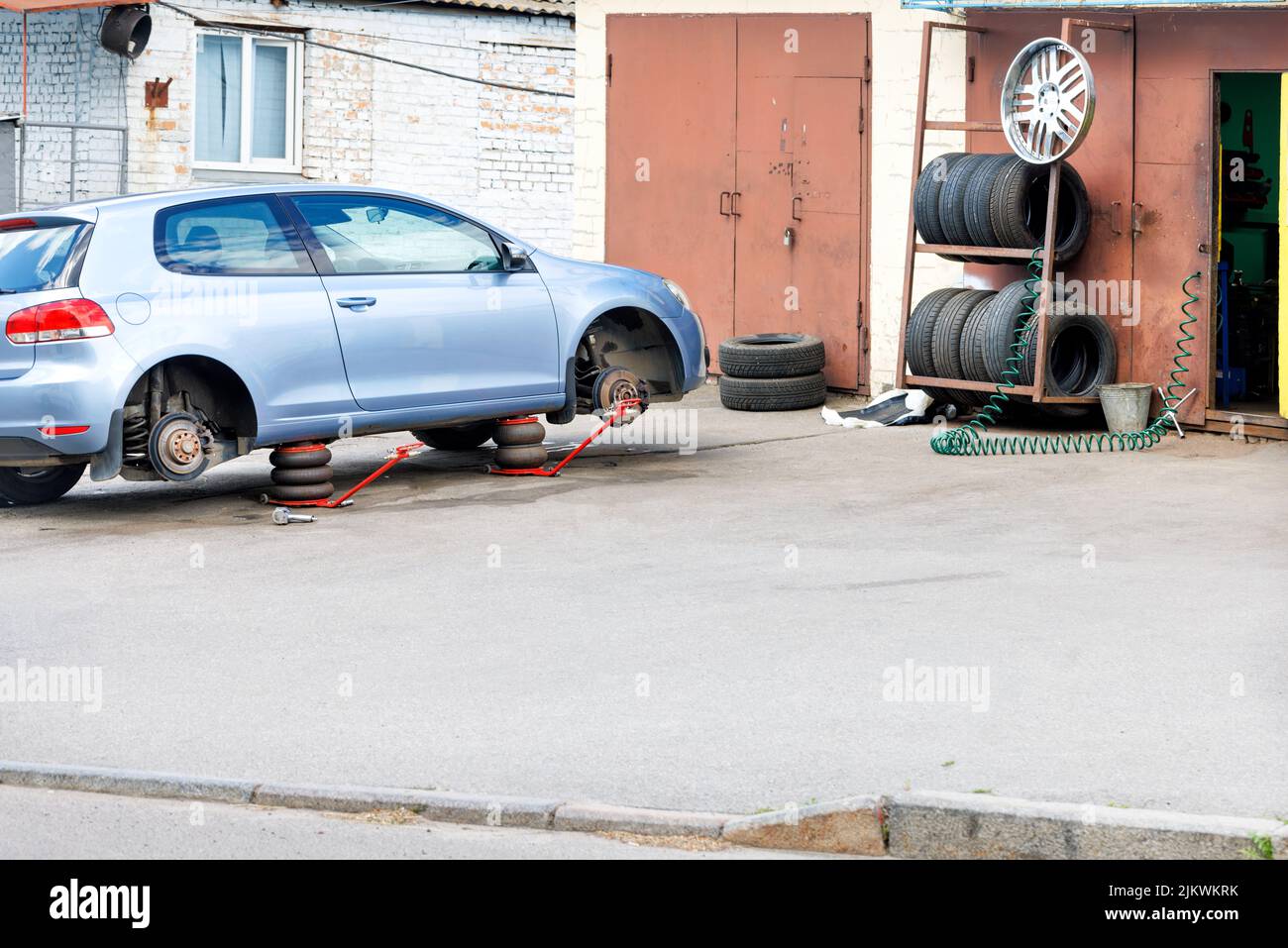 Tire workshop and replacement of old wheels on a car. On the one hand, the car is on air jacks. Copy space. Stock Photo