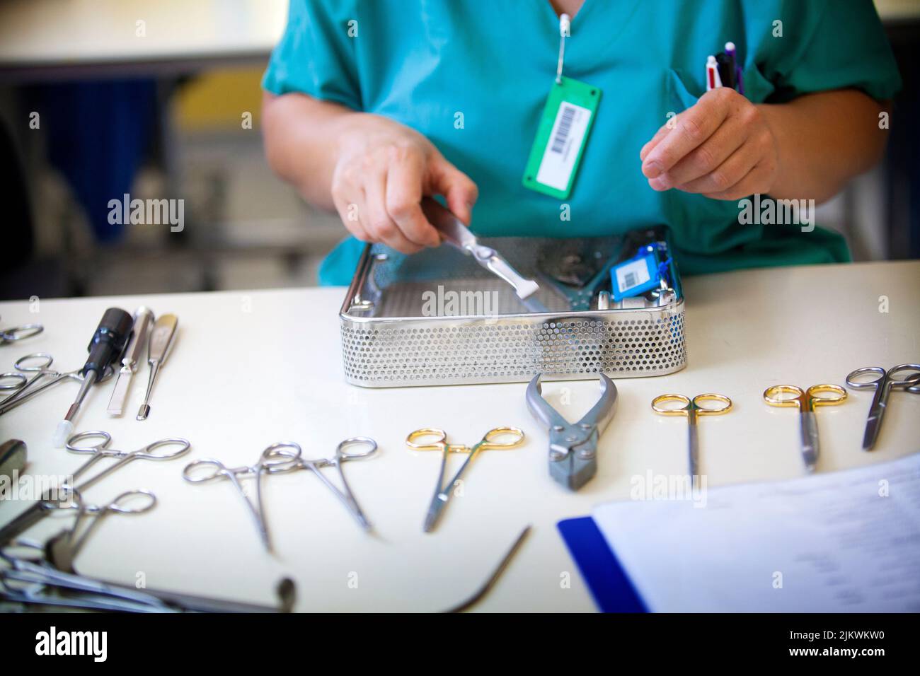 Before sterilization of surgical instruments, a nursing assistant recomposes the boxes of instruments used in the operating room. Stock Photo