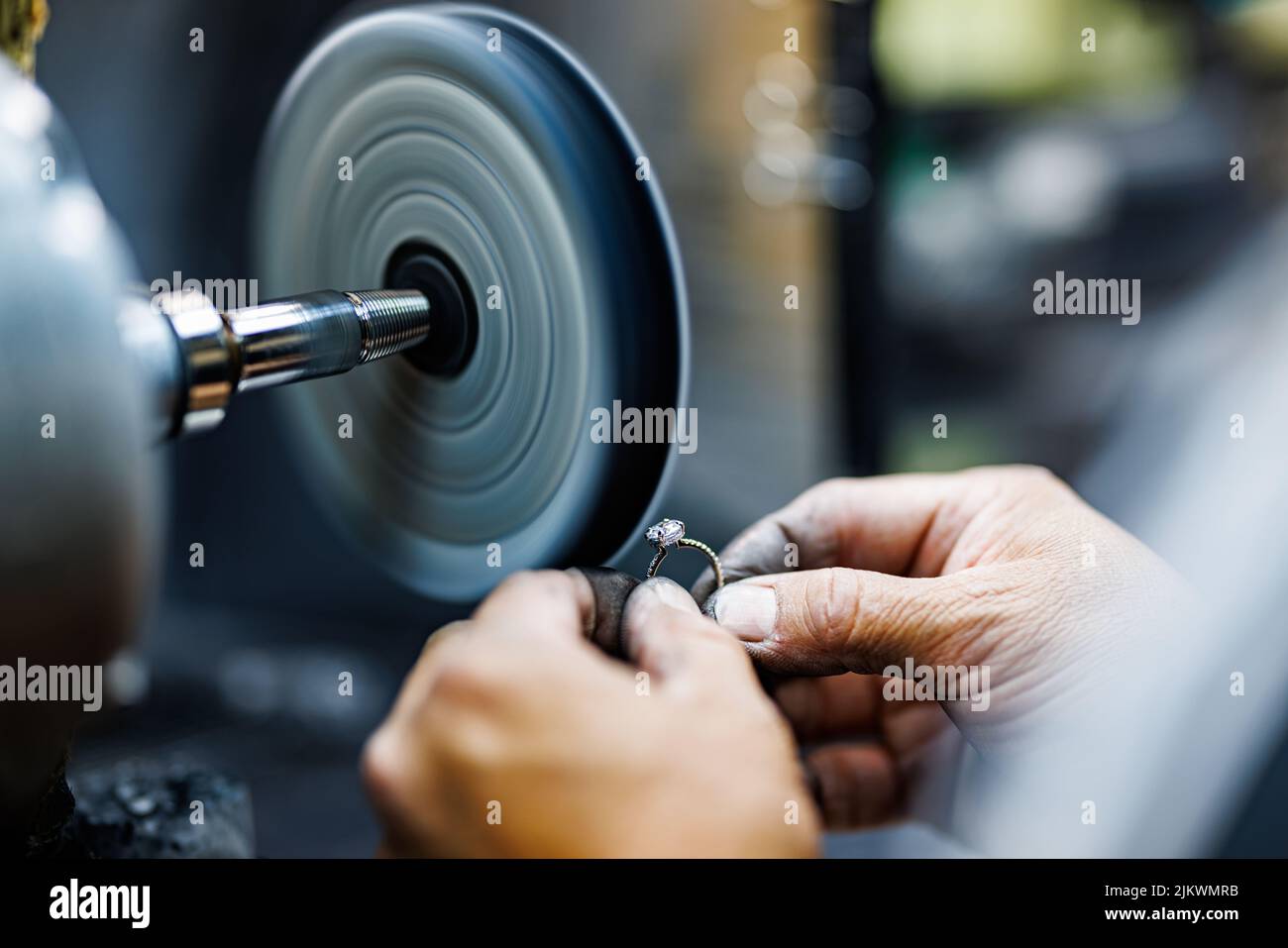 A male hand engraving the stone of a ring on a machine in a factory