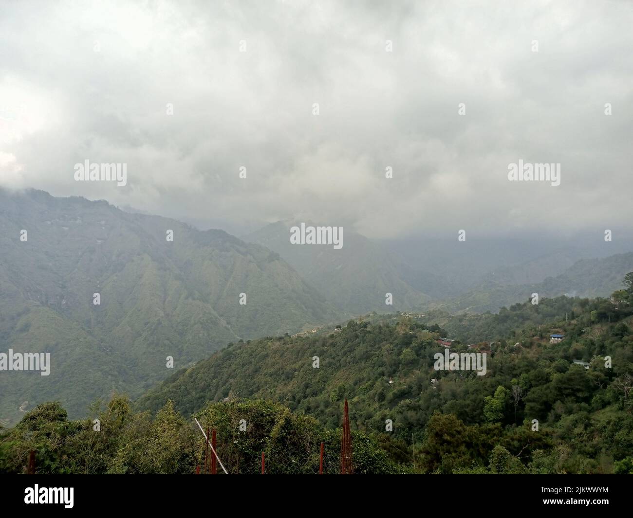 A beautiful landscape view of green Mountain with fog on the gray cloudy sky Stock Photo