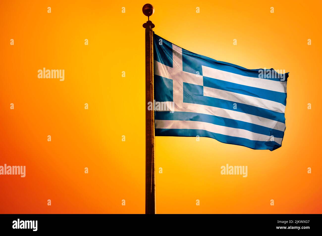 The national flag of Greece on a flagpole isolated on an orange