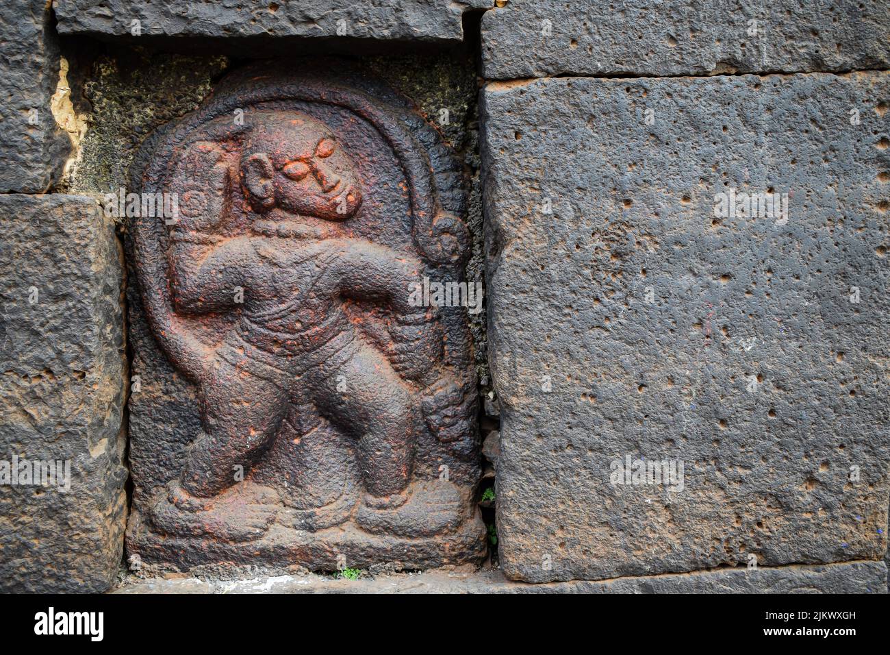 Stock photo of Ancient ruined archeological sculpture of hindu god hanuman engraved on gray stone wall. Picture captured during sunny day at Kolhapur Stock Photo