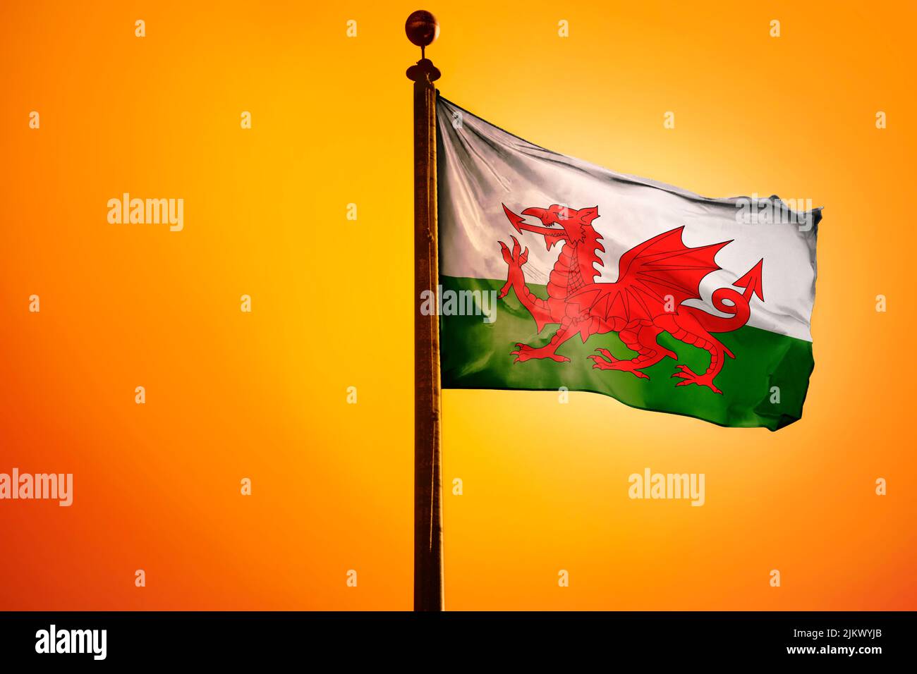 The waving flag of Wales on a bright yellow background Stock Photo