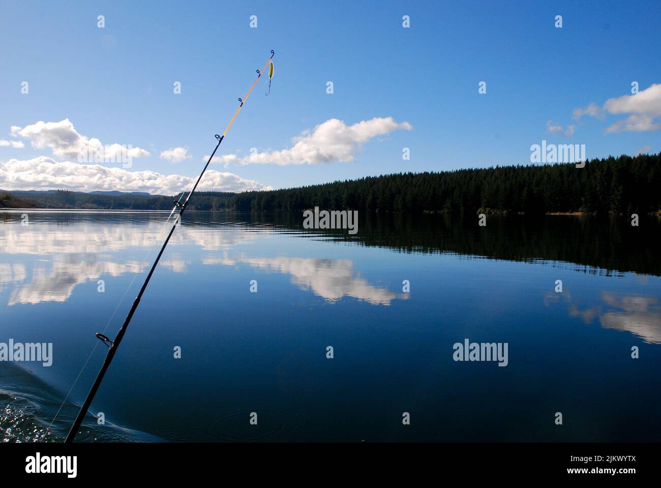 Reflections with lone fishing rod on Lake Maraetai, Mangakino, Taupo New Zealand Aotearoa Stock Photo
