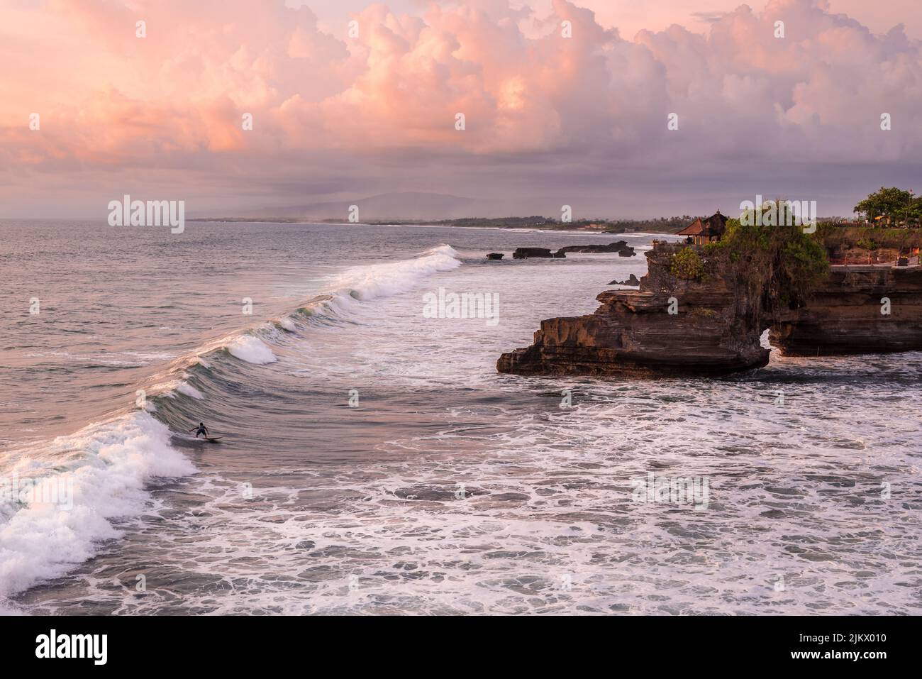 A scenic view of the coast and rocky island in Bali, Indonesia during sunset Stock Photo