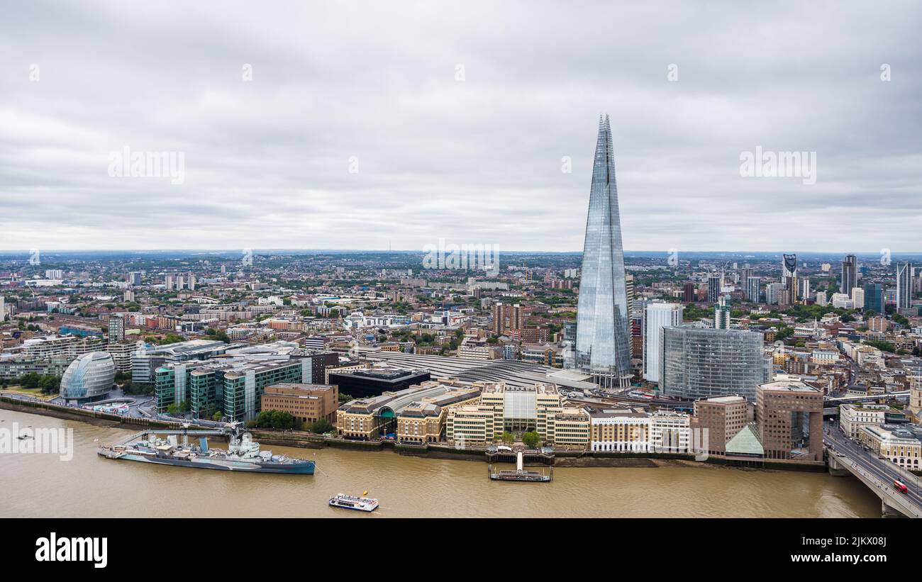 The Shard dominating the London skyline as it sits next to London Bridge train station.  HMS Belfast can be seen next to The Scoop and the City Hall B Stock Photo