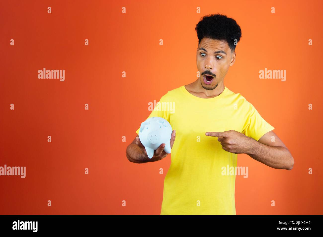 Handsome Black Man Holding a Piggy Bank Isolated on Orange Stock Photo ...