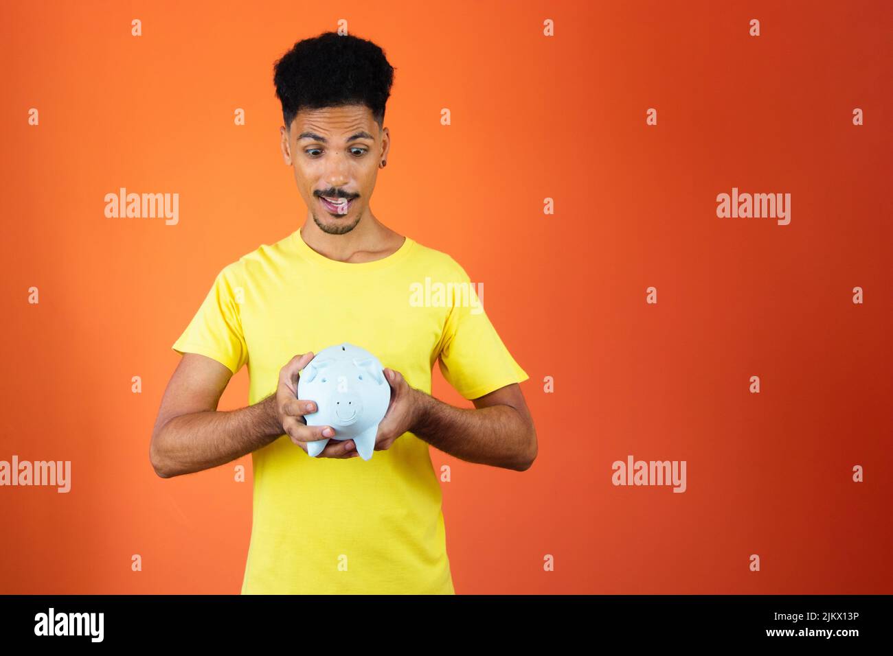 Handsome Black Man Holding a Piggy Bank Isolated on Orange Stock Photo ...