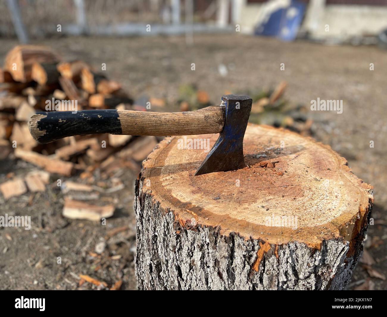 An old ax with a wooden handle stuck in a wooden log Stock Photo