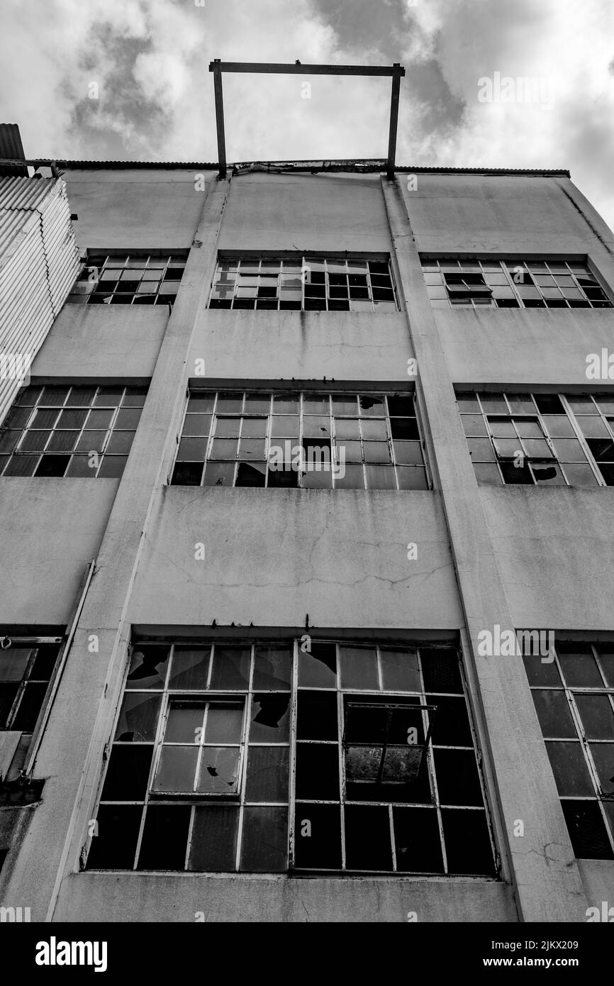 A vertical low angle grayscale shot of an old abandoned building with ...