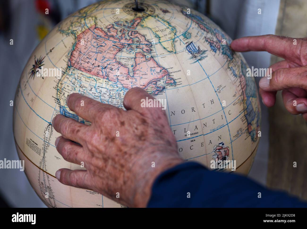 A man examines the North American continent and other geographial locations on a globe for sale in an antique shop. Stock Photo