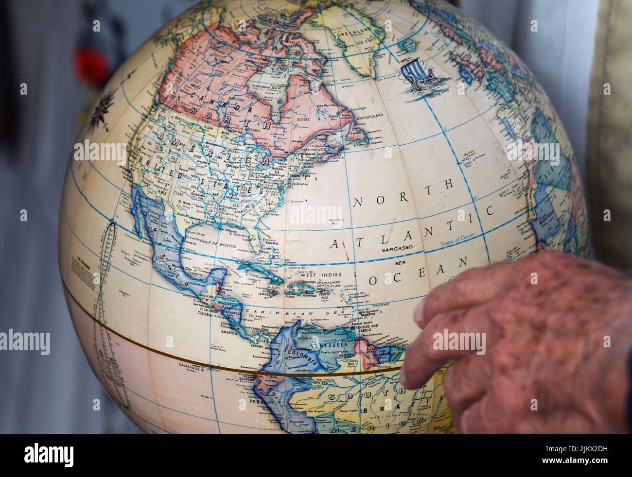 A man examines the North American continent and other geographial locations on a globe for sale in an antique shop. Stock Photo