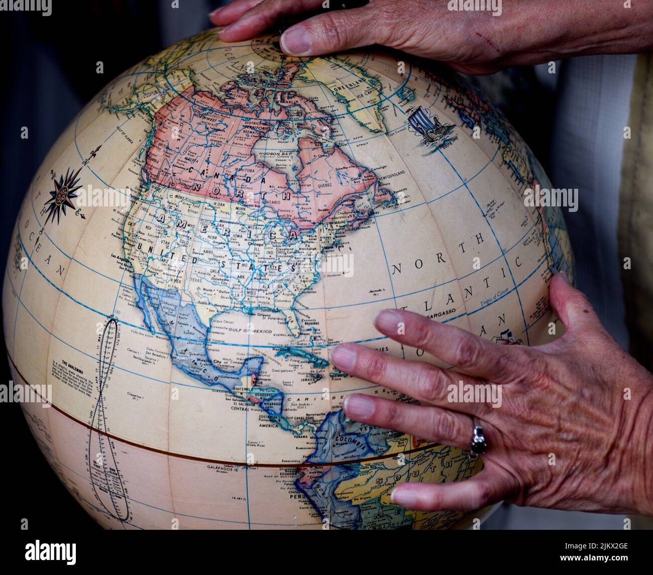 A woman examines the North American continent and other geographial locations on a globe for sale in an antique shop. Stock Photo
