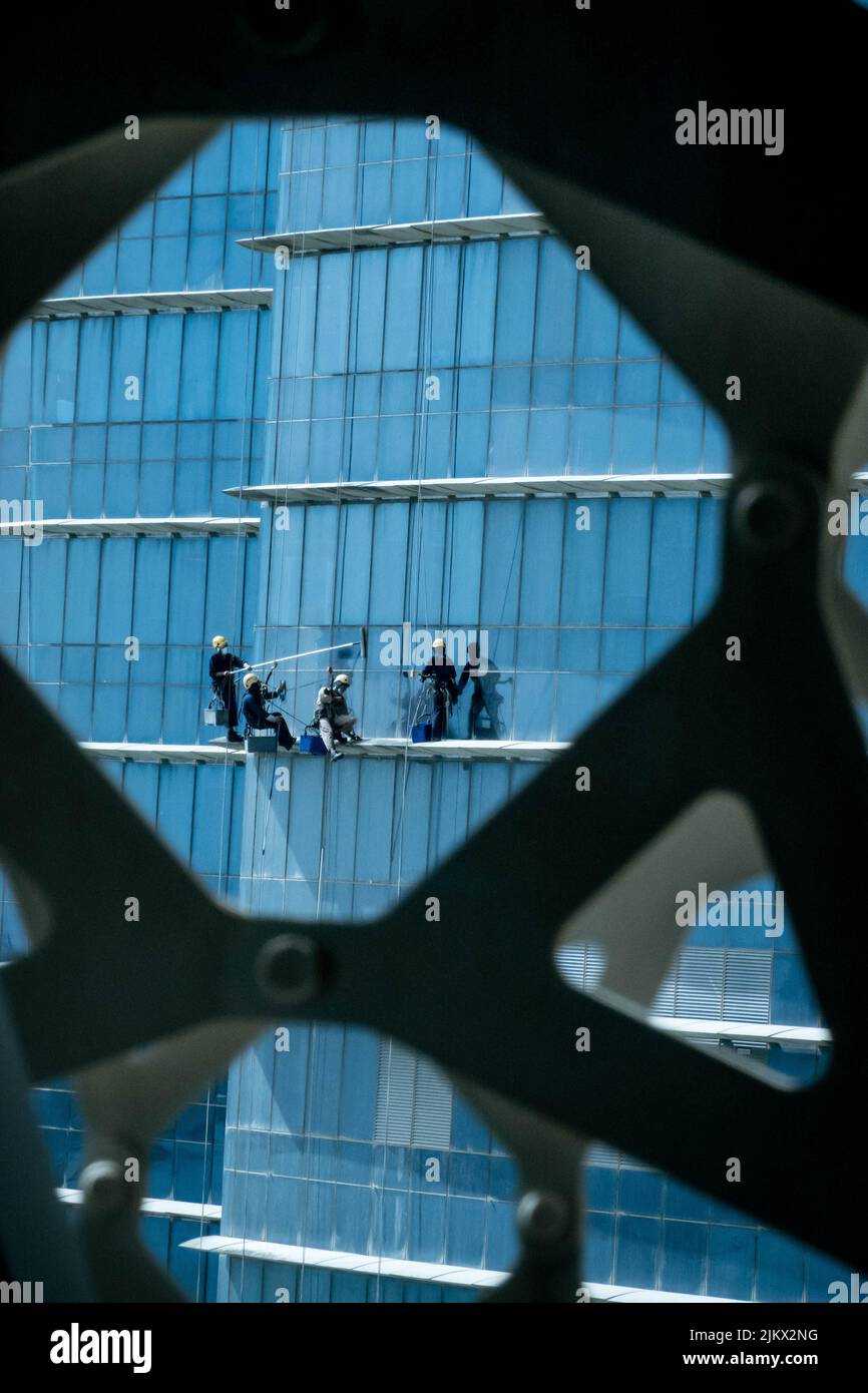 A vertical shot of men cleaning the windows of towers in Doha, Qatar