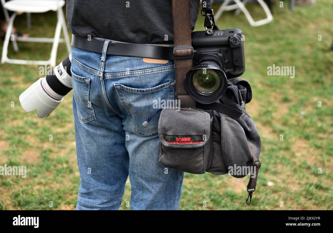A newspaper photographer with Canon cameras and a Domke camera bag takes photographs at an outdoor festival in Santa Fe, New Mexico. Stock Photo