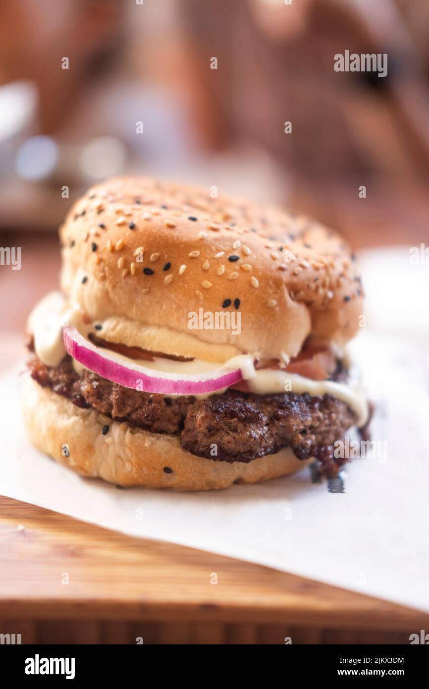 A vertical closeup of a delicious hamburger with onions, mayo and buns