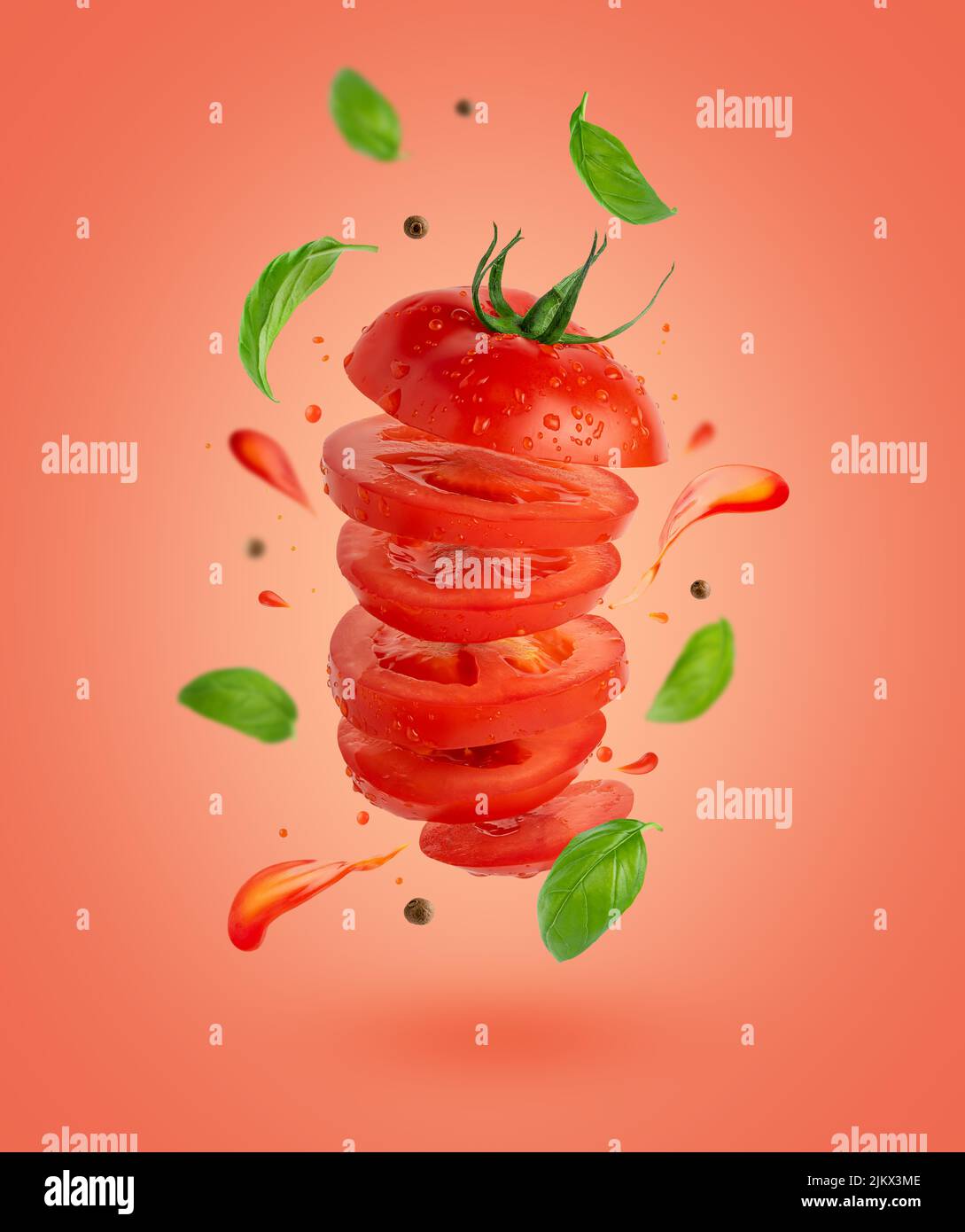 Flying sliced tomato with flowing splashes and basil leaves on red background. Stock Photo