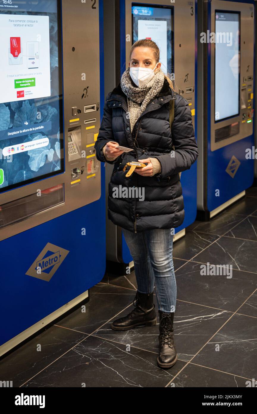 Young girl with a mask buying the metro ticket in the machine, it is winter in the Madrid metro Stock Photo