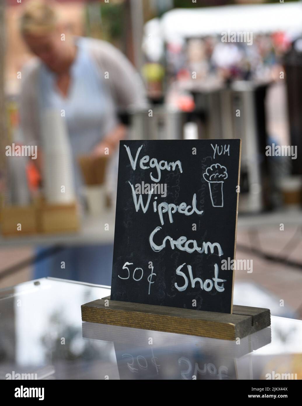 A food vendor offers vegan whipped cream shots on her baked desserts at a festival in Santa Fe, New Mexico. Stock Photo