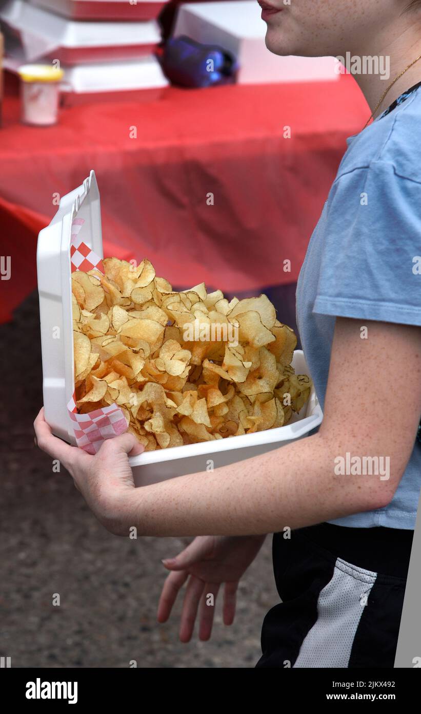 A young girl purchases a carton of ribbon fries from a food vendor at an outdoor festival in Santa Fe, New Mexico. Stock Photo