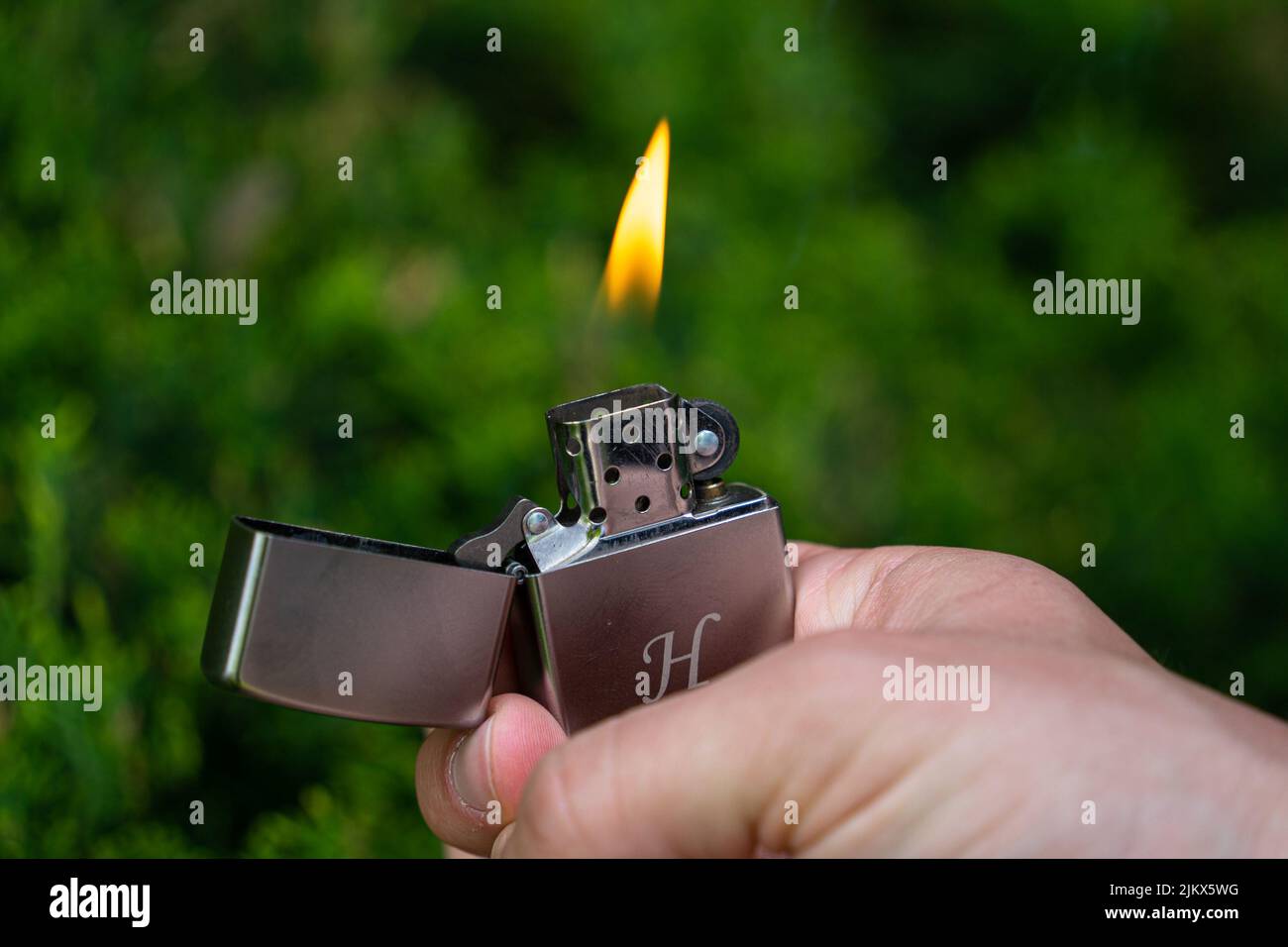 Budapest, Hungary - May 04 2022: Fancy metal cigarette lighter with flame being held in a white hand close up Stock Photo