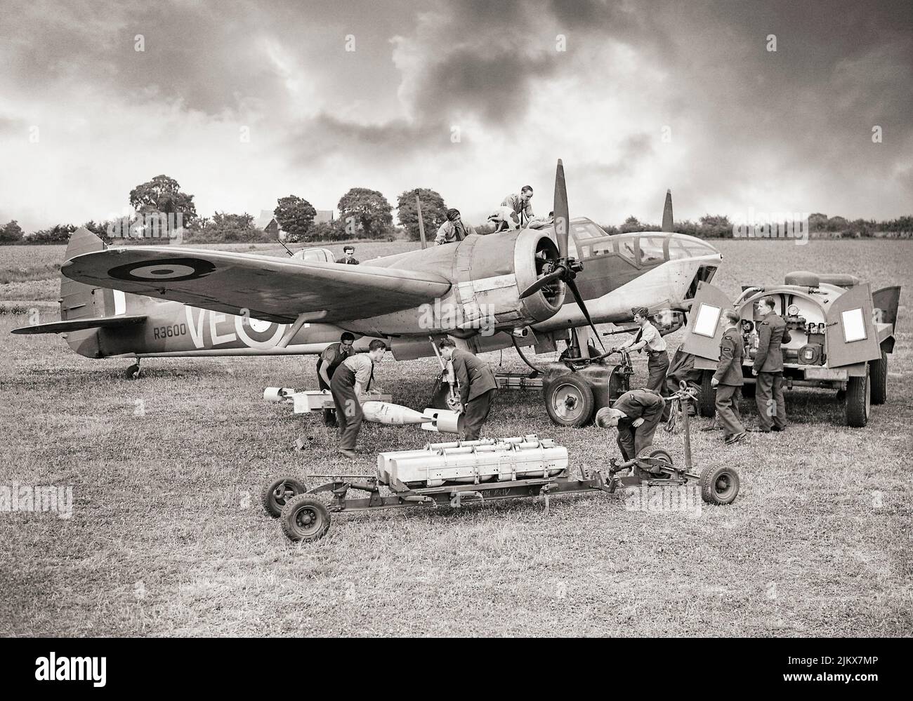 A Bristol Blenheim Mark IV, of No. 110 Squadron RAF, undergoes elaborate servicing at RAF Wattisham, Suffolk, England. Armourers unload 250-lb GP bombs and Small Bomb Containers (SBCs) of incendiaries from a trolley, while other groundcrew refuel the aircraft and attend to the engines, the cockpit and the gun-turret. Note the pet dog on the engine cowling. Stock Photo