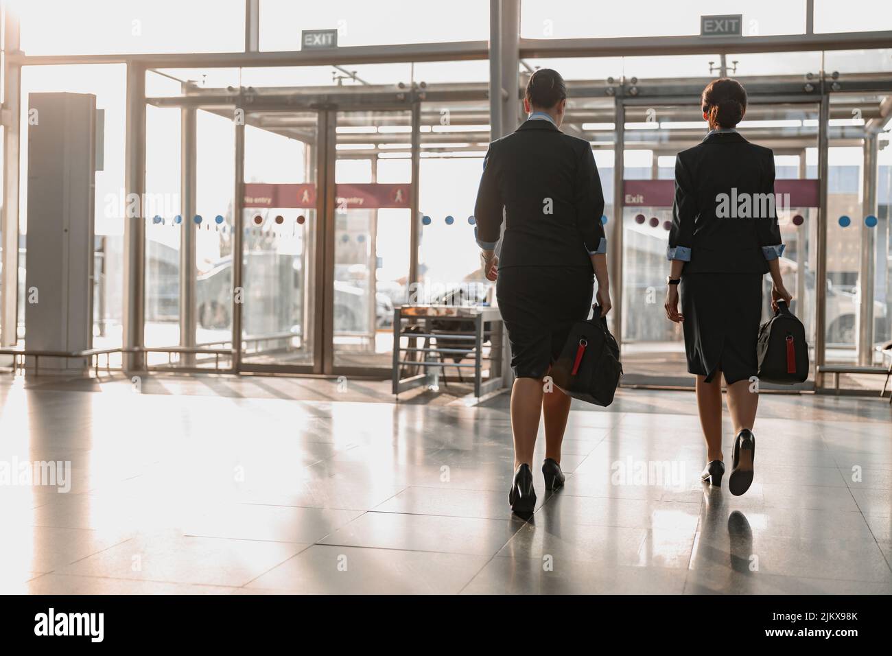 Two flight attendants holding bags and walking in the airport Stock