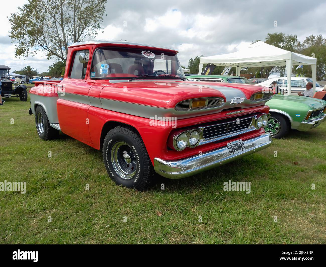 Chascomus, Argentina - Apr 09, 2022: Old red Chevrolet Chevy C10 Apache pickup truck 1960-1961. Green grass nature background. Utility or farming tool Stock Photo