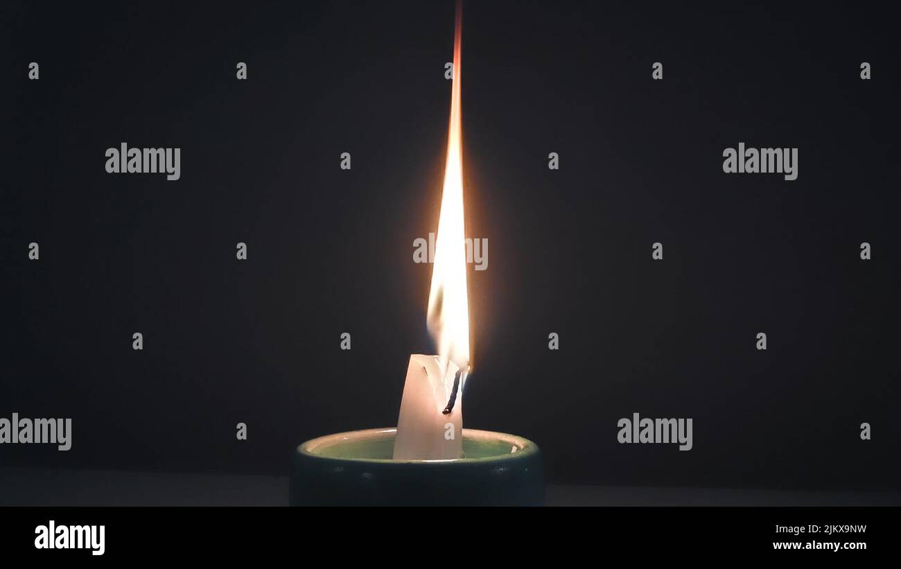 A closeup of a candle lighting up and illuminating in the darkness Stock Photo