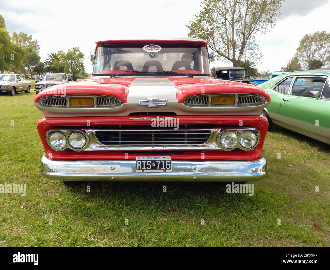 Chascomus, Argentina - Apr 09, 2022: Old red Chevrolet Chevy C10 Apache pickup truck 1960-1961. Front view. Grill. Green grass nature background. Util Stock Photo