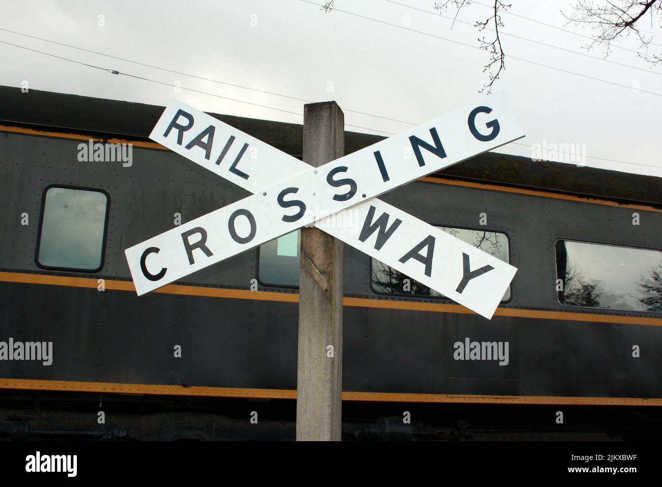 A Railway crossing sign with the train in the background in Langley, British Columbia, Canada Stock Photo