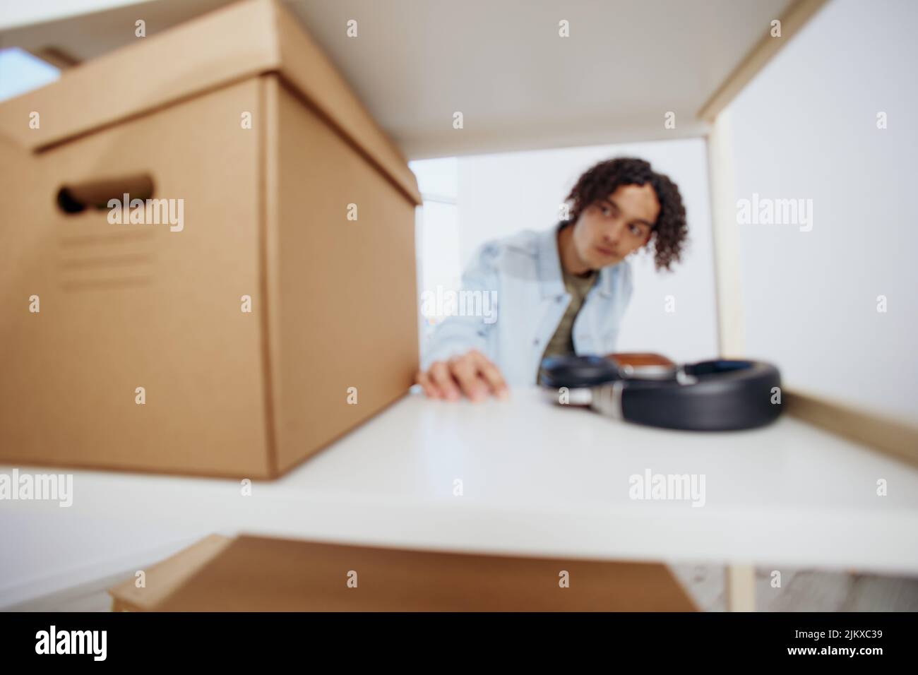 guy with curly hair unpacking things from boxes in the room sorting
