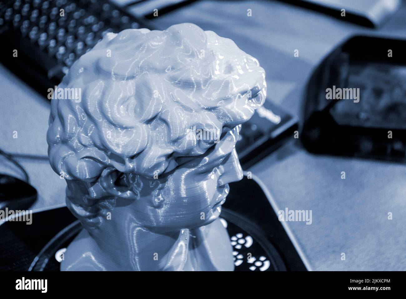 Gray human head on 3d printed close-up. An object prototype of a human head with hair printed by a 3D printer stands on a table. New modern additive 3D printing technology. Fused deposition modeling Stock Photo