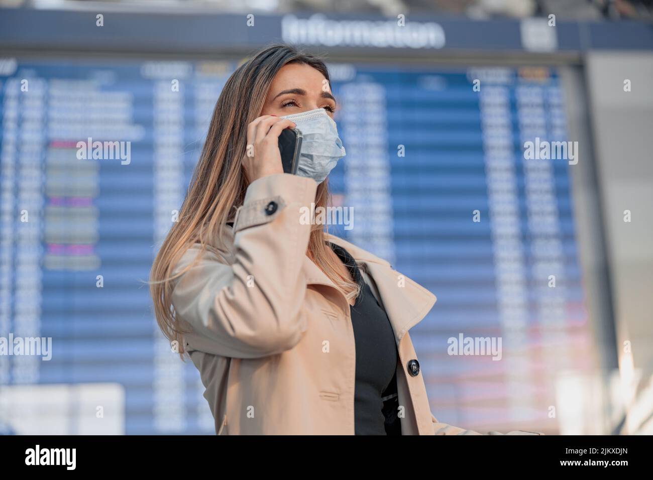 Young lady in mask talking smartphone in the airport Stock Photo
