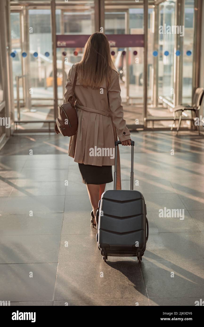 Lady with suitcase and backpack at the airport going to the exit Stock