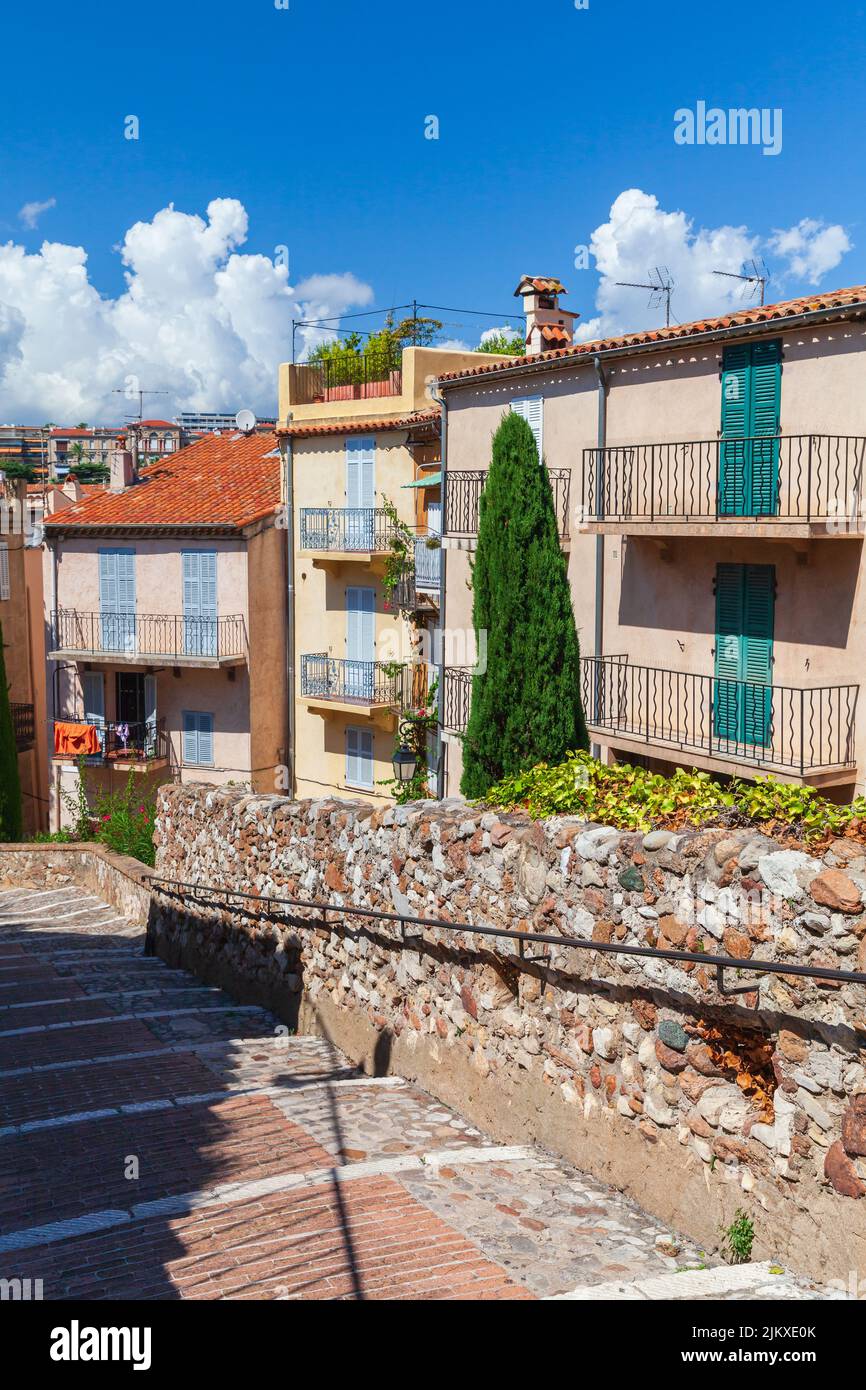 Vertical street view of Cannes, France. Old residential houses are on a narrow street on a sunny day Stock Photo