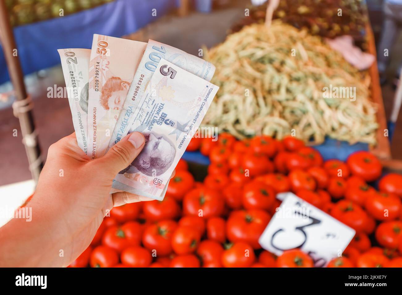 Turkish lira banknotes in hand against the background of vegetables at the farmer's market. The concept of consumer economy and inflation of the natio Stock Photo