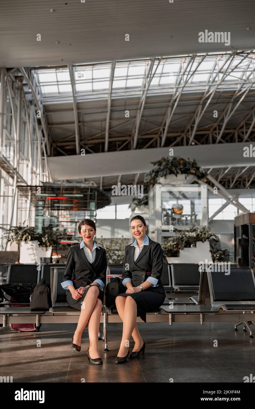 Two flight attendants sitting on the seats in the airport terminal Stock Photo Alamy